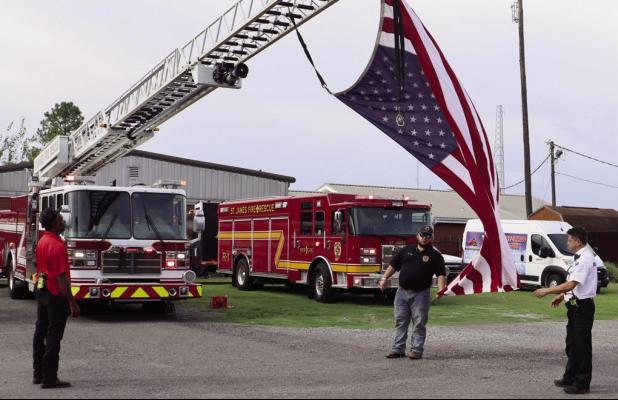 Members of the St. James Fire Department and Acadian Ambulance suspend a large American Flag on a ladder truck to commemorate the 25year anniversary of the September 11, 2001, terrorist attacks on the World Trade Center buildings in New York City, the Pen