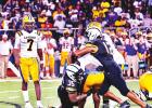 Two Wildcat defenders take down a Bulldog ball carrier last Friday in Vacherie. The Bulldogs, after losing the previous four matchups, beat the ‘Cats 41-19. Photo by Oliver Hooker “Lunchtime” – Lutcher Quarterback Serves Up Much Needed Victory Over Rival Wildcats