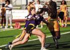 Lady Bulldogs Taylor Tregre (#10) and Aubrey Madere pull the flag off a St. James Wildcat runner. Photo by Tony Schexnayder
